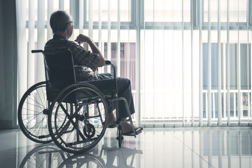 elderly person sitting in a wheel chair by a window