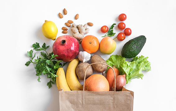 fruits and vegetables coming out of a paper bag laying on a table 