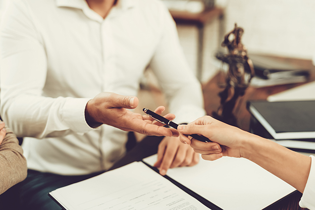 person handing a pen to another person