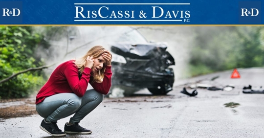 Woman kneeling next to crashed car
