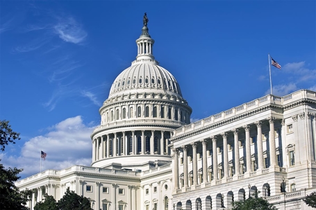 The US Capitol in front of a bright blue sky with a few clouds