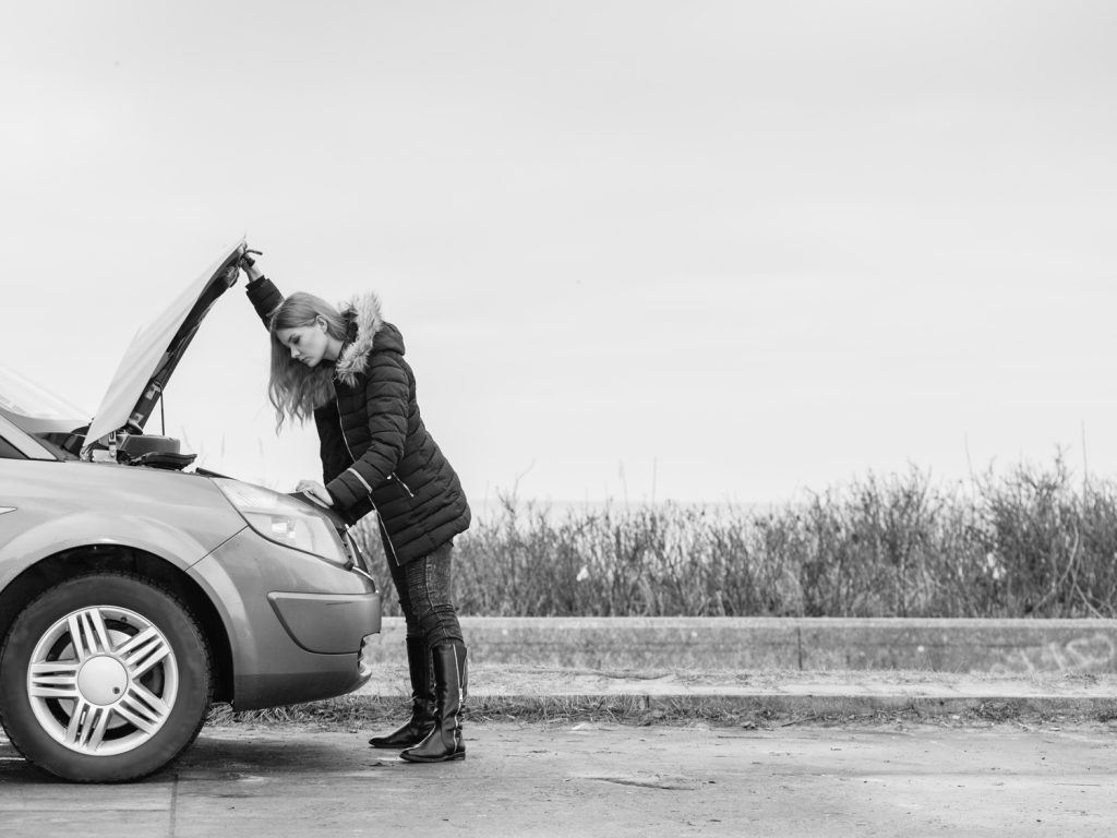 woman opening the hood of a car and looking at the engine