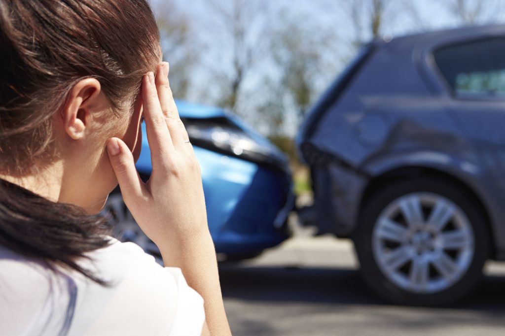 Woman Touching her head Looking at a Car Accident