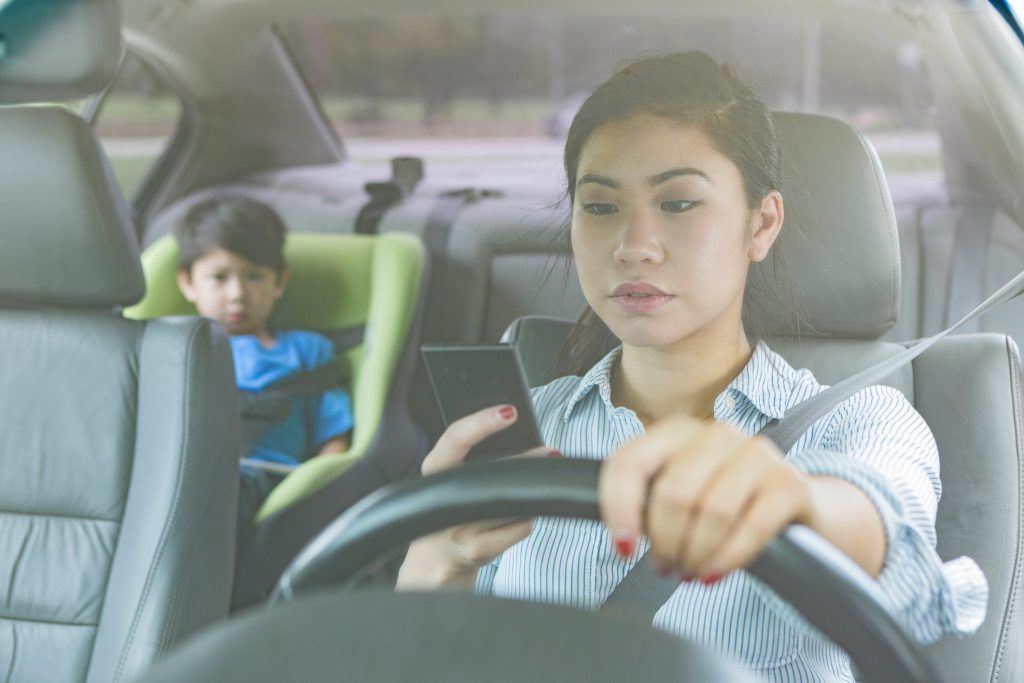Woman looking at her cell phone while driving