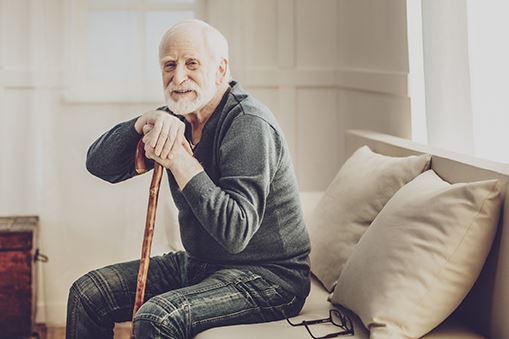 Elderly Man Sitting on a Couch Holding a Cane