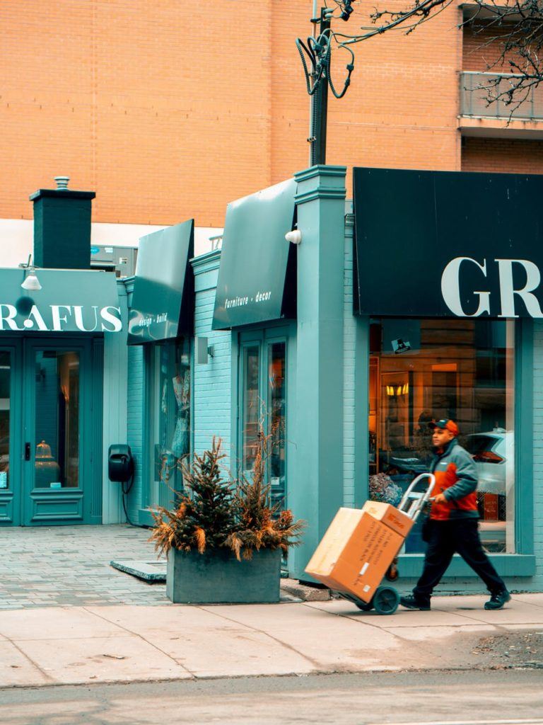 package delivery man pushing cart outside store